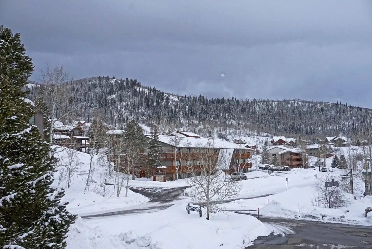 A winter scene featuring snow-covered landscapes, mountains in the background, cozy cabins and buildings, and a road intersection. The image conveys a sense of adventure and tranquility, suitable for outdoor activities like skiing, snowboarding, and winter hiking.