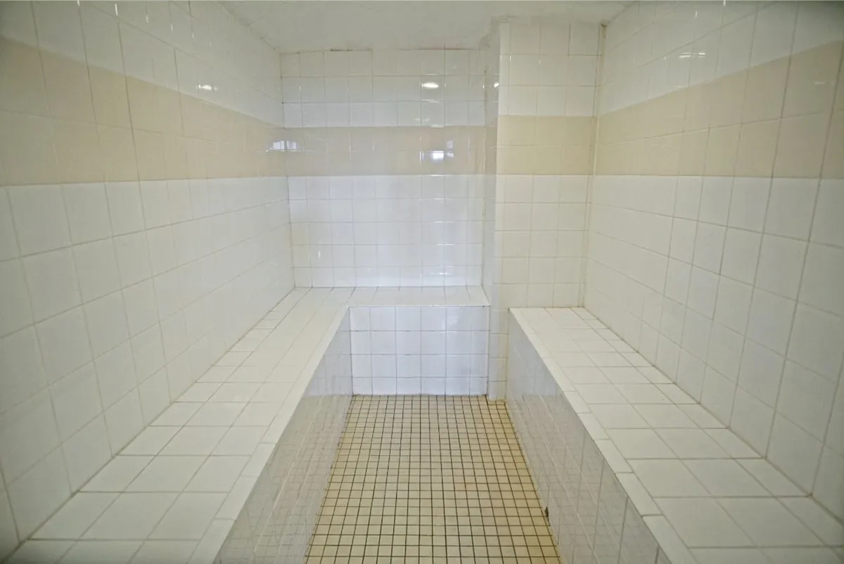 A bright, tiled interior space features built-in benches and a horizontal stripe pattern, evoking a clean and welcoming wellness area. This is suggestive of the property’s community sauna or steam room, a perfect post-adventure amenity.