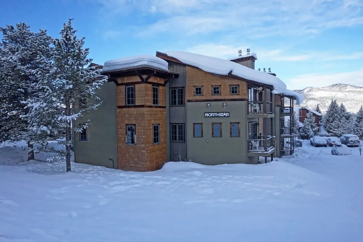 The Northstar building is pictured nestled in a snow-covered landscape, framed by evergreen trees and pristine white snow. The scene is tranquil, with the building serving as a clear reference point for proximity to Steamboat’s ski slopes and winter activities.