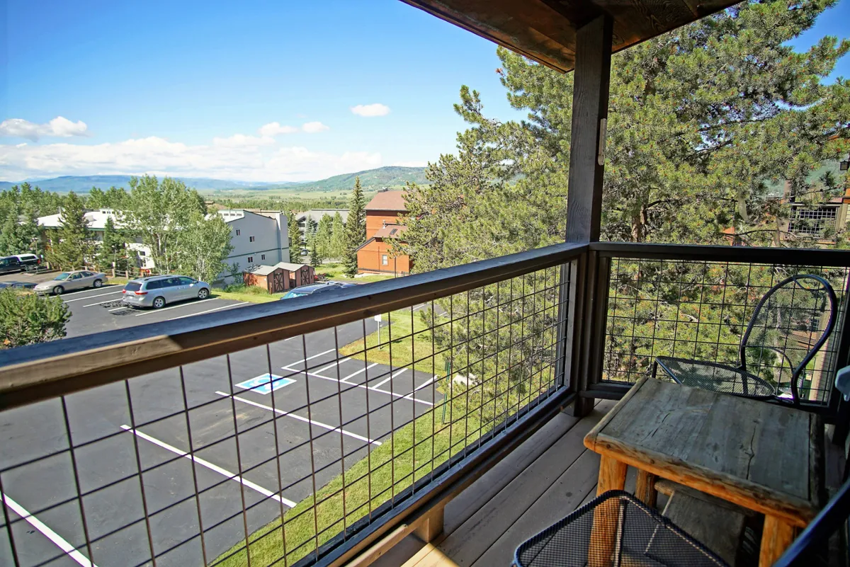 A peaceful private balcony scene with a classic wooden railing, lush greenery, and a sweeping view of the mountains. The setup hints at a perfect spot to savor coffee or watch the sunset after a day of adventure.